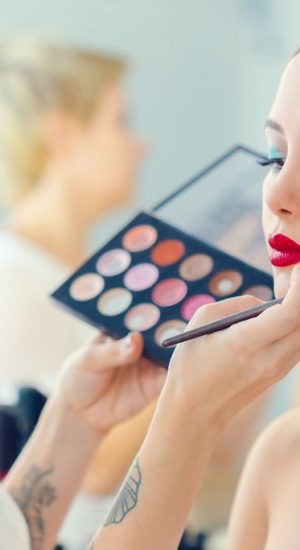 make up artist doing professional make up of young woman